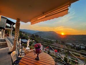- une table sur un balcon avec vue sur le coucher du soleil dans l'établissement Stone Maisonettes, à Aigio