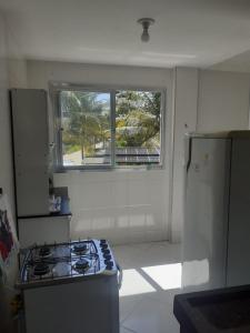a kitchen with a stove and a window at Apartamento 204 vista para o mar e piscina in Piúma