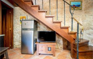 a kitchen with a refrigerator and a tv and stairs at Awesome Home In Muros With Wifi And 2 Bedrooms in Muros