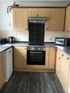 a kitchen with wooden cabinets and a stove top oven at Accomodation for contractors & professionals 3 bed house with parking in Lighthorne