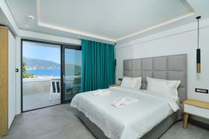 a bedroom with a large white bed and a balcony at Aloe Elegant Suites in Skala Potamias