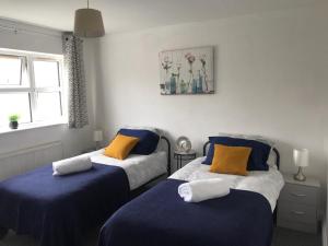 a bedroom with two beds with blue and yellow pillows at Accomodation for contractors & professionals 3 bed house with parking in Lighthorne