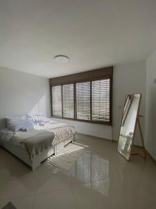 a white bedroom with a bed and a mirror at Vibe Place in Netanya