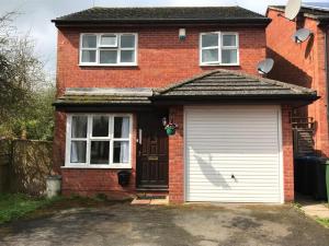 a red brick house with a white garage at Accomodation for contractors & professionals 3 bed house with parking in Lighthorne