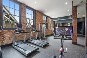 un gimnasio con varias máquinas de correr y TV en Roami at The Lola en Nueva Orleans