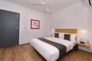 a bedroom with a large white bed and a black door at Townhouse Function Inn Near Chaudhary Charan Singh International Airport in Charbagh