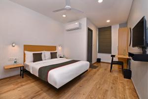 a bedroom with a large bed and a flat screen tv at Townhouse Function Inn Near Chaudhary Charan Singh International Airport in Charbagh