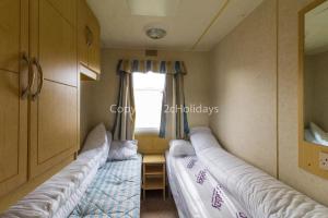 two beds in a room with a window at 8 Berth Caravan At California Cliffs Holiday Park In Norfolk Ref 50007d in Great Yarmouth