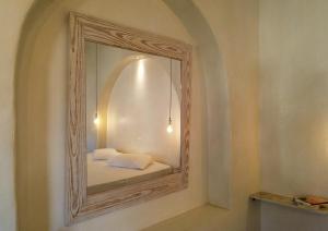 a mirror on a wall with a bed in a room at Mistral-Patmos in Patmos