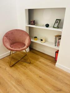 einen rosa Stuhl in einem Zimmer mit Bücherregal in der Unterkunft Charming parisian apartment in Paris
