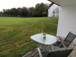 Una botella de vino sentada en una mesa blanca con dos sillas en St Anns Cottage 9, en Gunnislake