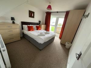 a bedroom with a bed with orange pillows and a window at St Anns Cottage 9 in Gunnislake
