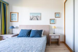 a bedroom with a bed with blue sheets and two tables at 1 Bed With Balcony Pool and Tennis in Quarteira