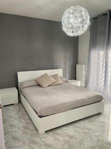 um quarto com uma cama branca e um lustre em Blue Wave Apartment em Bari