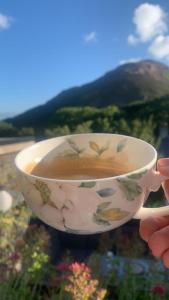 a person holding a cup of coffee with mountains in the background at Woodbriar in Conwy