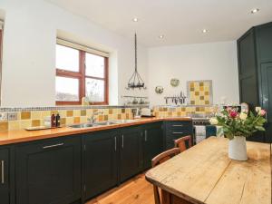 a kitchen with green cabinets and a wooden table at Oak Barn in Cullompton