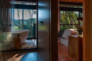 a bathroom with a tub and a bedroom with a bed at Green Barn Hotel & Bistro in Urubici