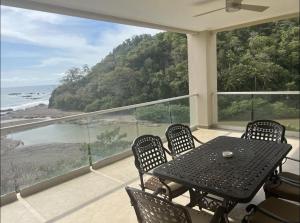 a table and chairs on a balcony with a view of the ocean at Break Water Point Penthouse 7th Floor in Jacó
