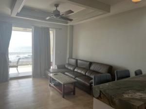 a living room with a leather couch and a table at Break Water Point Penthouse 7th Floor in Jacó