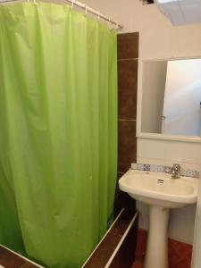 a bathroom with a green shower curtain and a sink at Hotel Capric in Viña del Mar