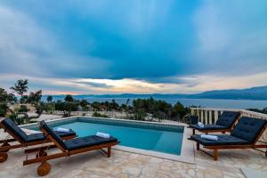 una piscina con sillas y vistas al agua en Villa Supetra, en Supetar