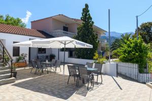 un patio con mesas, sillas y una sombrilla en Aspa's House, en Limenas