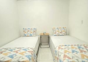two twin beds in a room with white walls at Residencial Lassonde Guest House in David