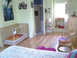 Salvagnac-Cajarc的住宿－Chez carpet，一间卧室设有一张婴儿床和两把椅子,铺有木地板。