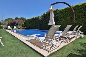 a group of chairs and an umbrella next to a pool at Alacaat Otel in Alaçatı
