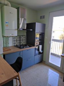 uma cozinha com armários azuis e um forno com placa de fogão em Grand Appartement Ensoleillé avec Parking em Nîmes