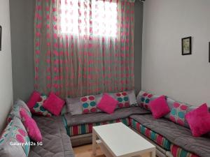 - un salon avec un canapé et des oreillers roses dans l'établissement Appartement entier à une chambre à coucher, à Agadir
