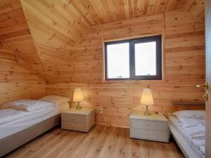 two beds in a wooden room with two lamps at Mieleńskie Piaski in Mielno