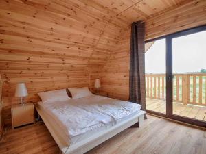 a bed in a wooden room with a large window at Mieleńskie Piaski in Mielno