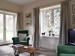 a living room with green chairs and a window at Glenearn Lodge Cottage in Bridge of Earn