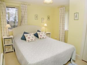 a bedroom with a white bed with pillows and a window at Glenearn Lodge Cottage in Bridge of Earn
