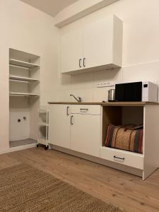 a kitchen with white cabinets and a microwave at Cozy apartment close to Palmovka in Prague