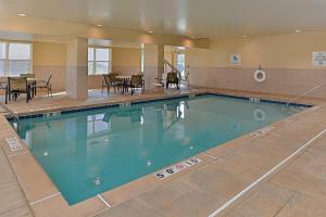 uma grande piscina num ginásio com mesas e cadeiras em Holiday Inn Express Hotel & Suites St. Louis West-O'Fallon, an IHG Hotel em O'Fallon