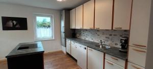 uma cozinha com armários brancos, um lavatório e uma janela em Ferienhaus Familienzeit em Schiefling am See