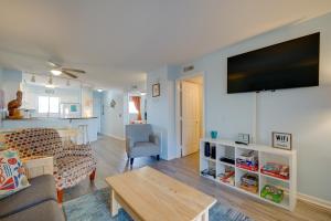 a living room with a couch and a tv on a wall at Oceanfront Carolina Beach Condo with Pool and Views! in Carolina Beach