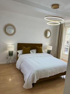 una camera bianca con un grande letto e due specchi di Beau duplex au centre Ville. a Mantes-la-Jolie
