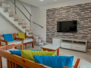 a living room with a tv on a brick wall at 7 Heaven Arraial D'ajuda - Alto da Pitinga - Ararat in Arraial d'Ajuda