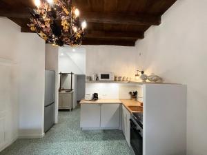 una cucina con armadi bianchi e lampadario pendente di Housica & Co 2 a Ucciani