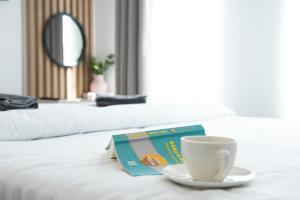 a book and a cup of coffee on a bed at Alternativ 2 Residence Central in Timişoara