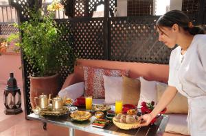 una mujer sosteniendo una bandeja de comida en una mesa en Riad Saba, en Marrakech