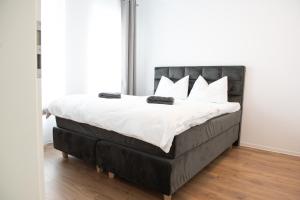 uma cama com cabeceira preta e almofadas brancas em Alternativ 2 Residence Central em Timisoara