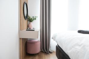 a bedroom with a bed and a mirror and a pink stool at Alternativ 2 Residence Central in Timişoara