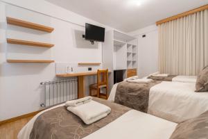 ein Hotelzimmer mit zwei Betten und einem Flachbildfernseher in der Unterkunft Hotel Sol del Sur in Esquel