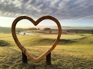 a wooden heart on a post in a field at Apartmán u potoka in Kestřany