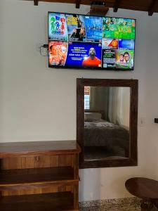 une pièce avec un miroir et une télévision à écran plat au mur dans l'établissement chale ype, à Monte Verde