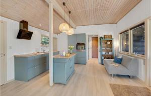 une grande cuisine avec des placards bleus et un canapé dans l'établissement Awesome Home In Blvand With 3 Bedrooms And Wifi, à Blåvand